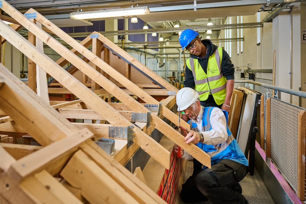 Carpentry lecturer showing student how to measure roof beams